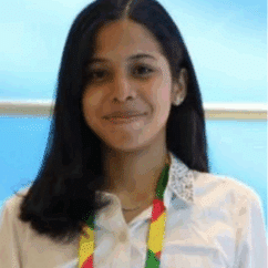 Alexandra Andrea Gómez Fernández smiling at the camera against a sky blue background.